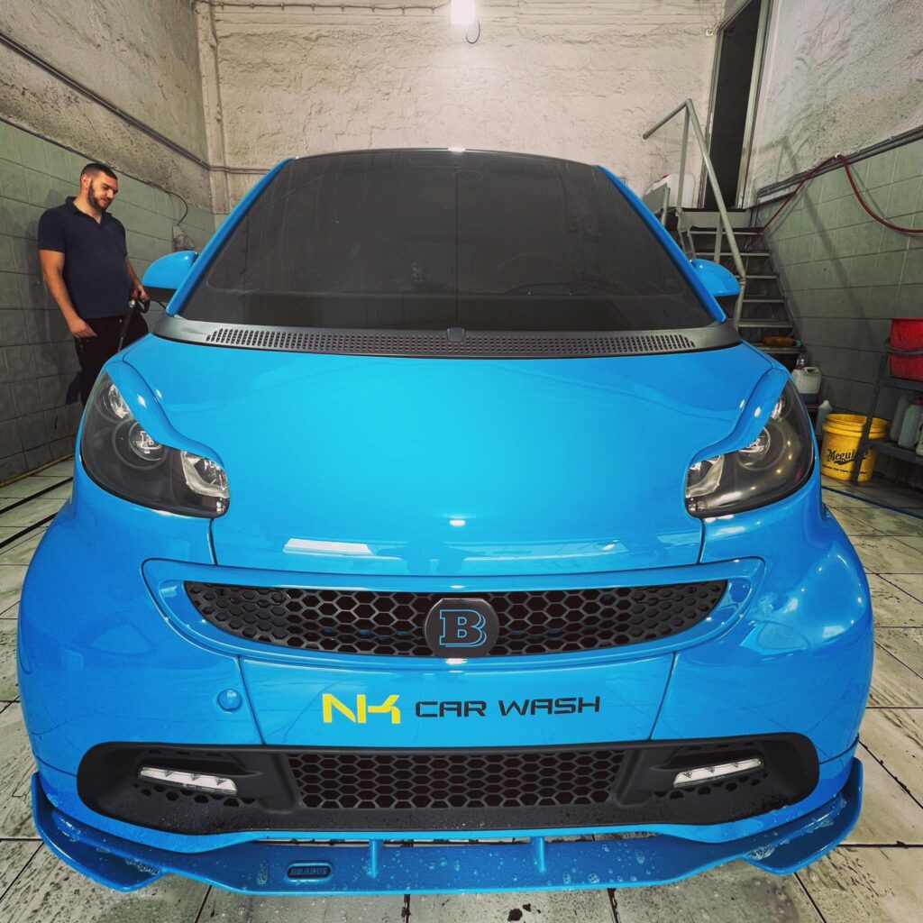 Μπλε αυτοκίνητο με το λογότυπο του NK Car Wash μετά από ολοκληρωμένη περιποίηση.