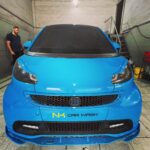 Μπλε αυτοκίνητο με το λογότυπο του NK Car Wash μετά από ολοκληρωμένη περιποίηση.